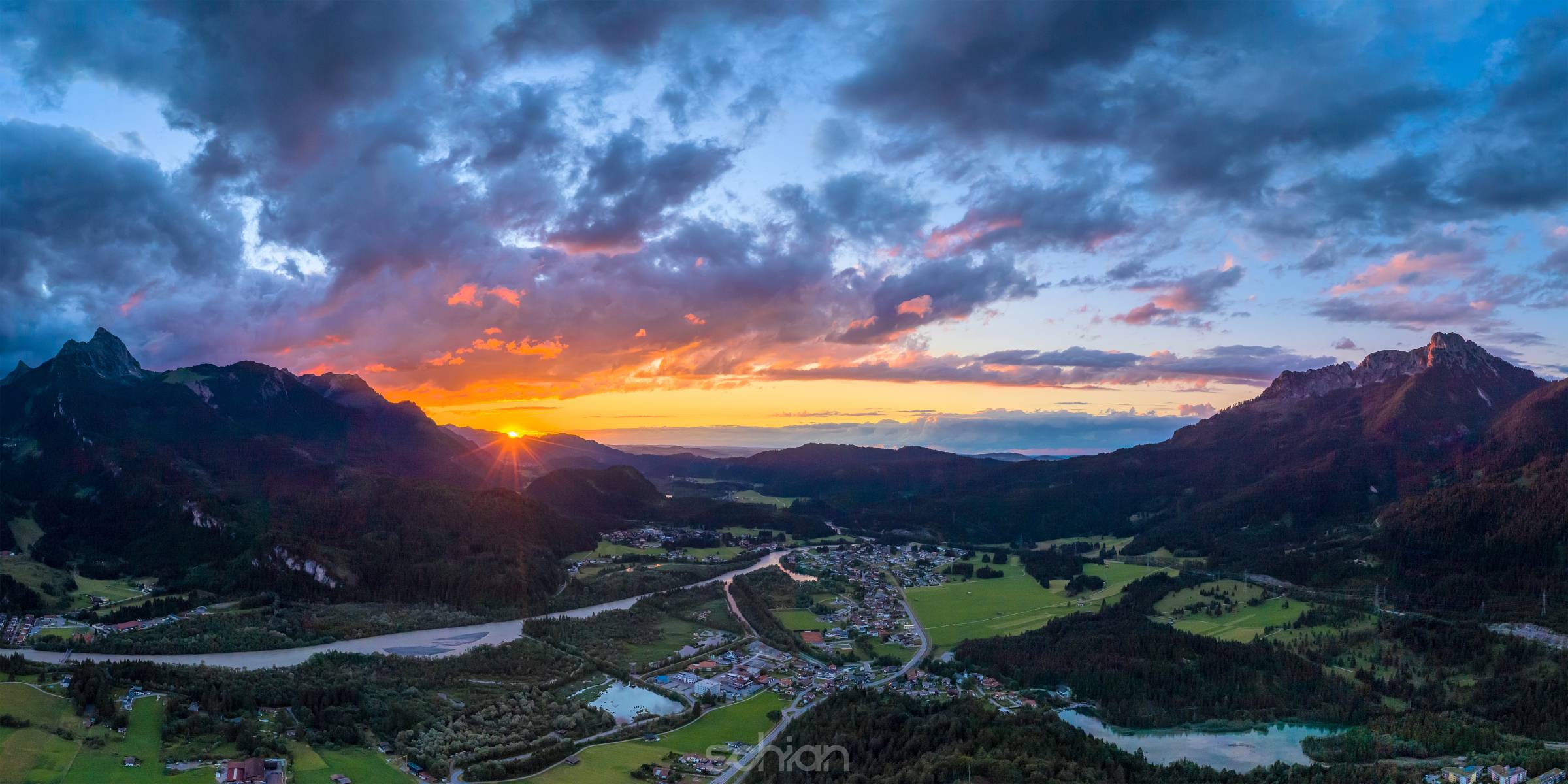 hiding sun behind mountain chain hahnenkamm with view to village pflach in reutte tirol