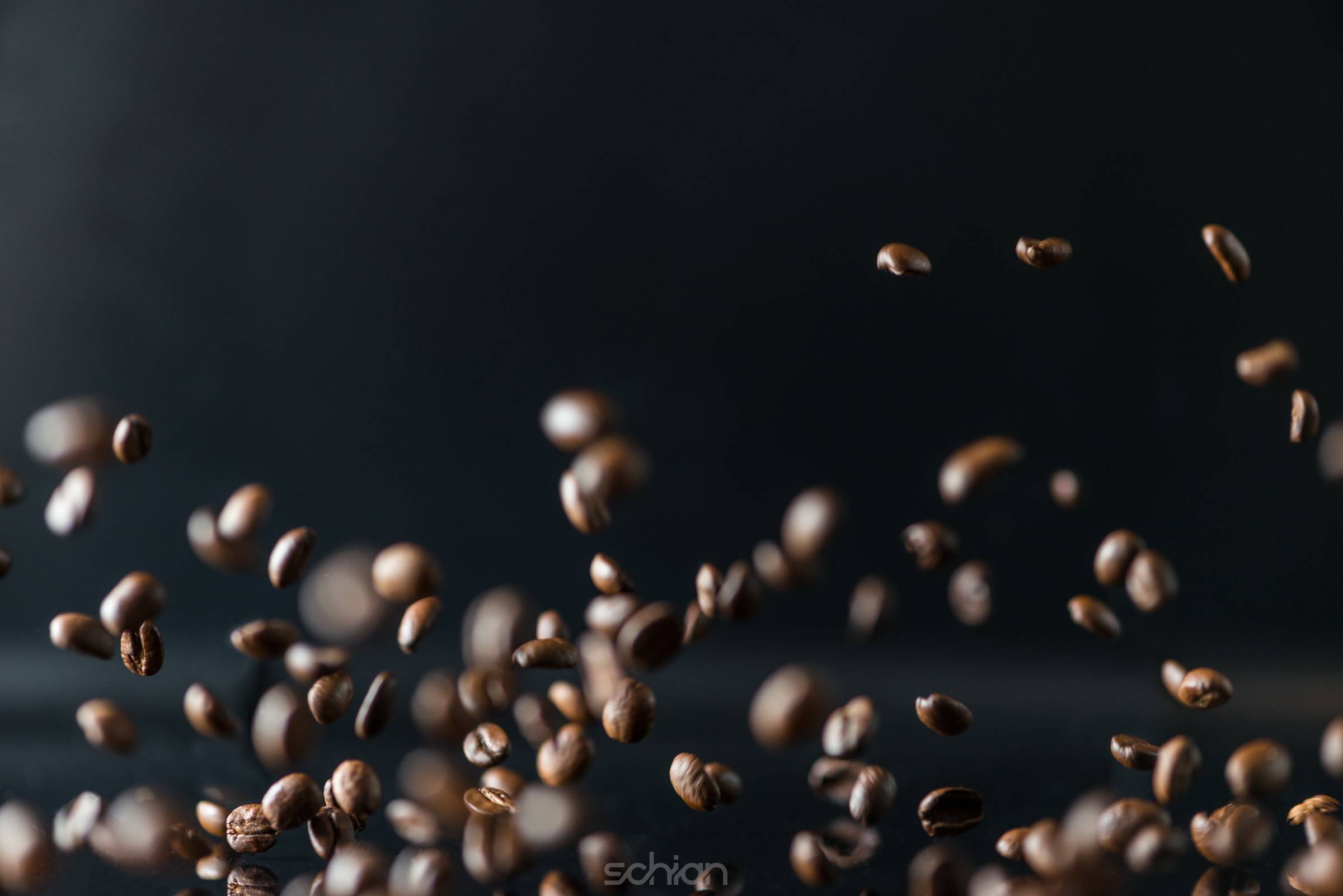 many flying coffee beans on black background