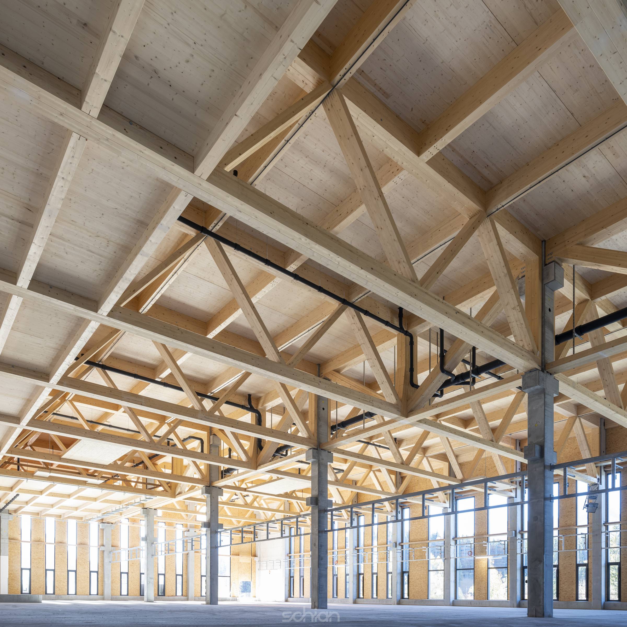 modern industrial hall with timber trusses and prefabricated concrete columns with many glass facade elements