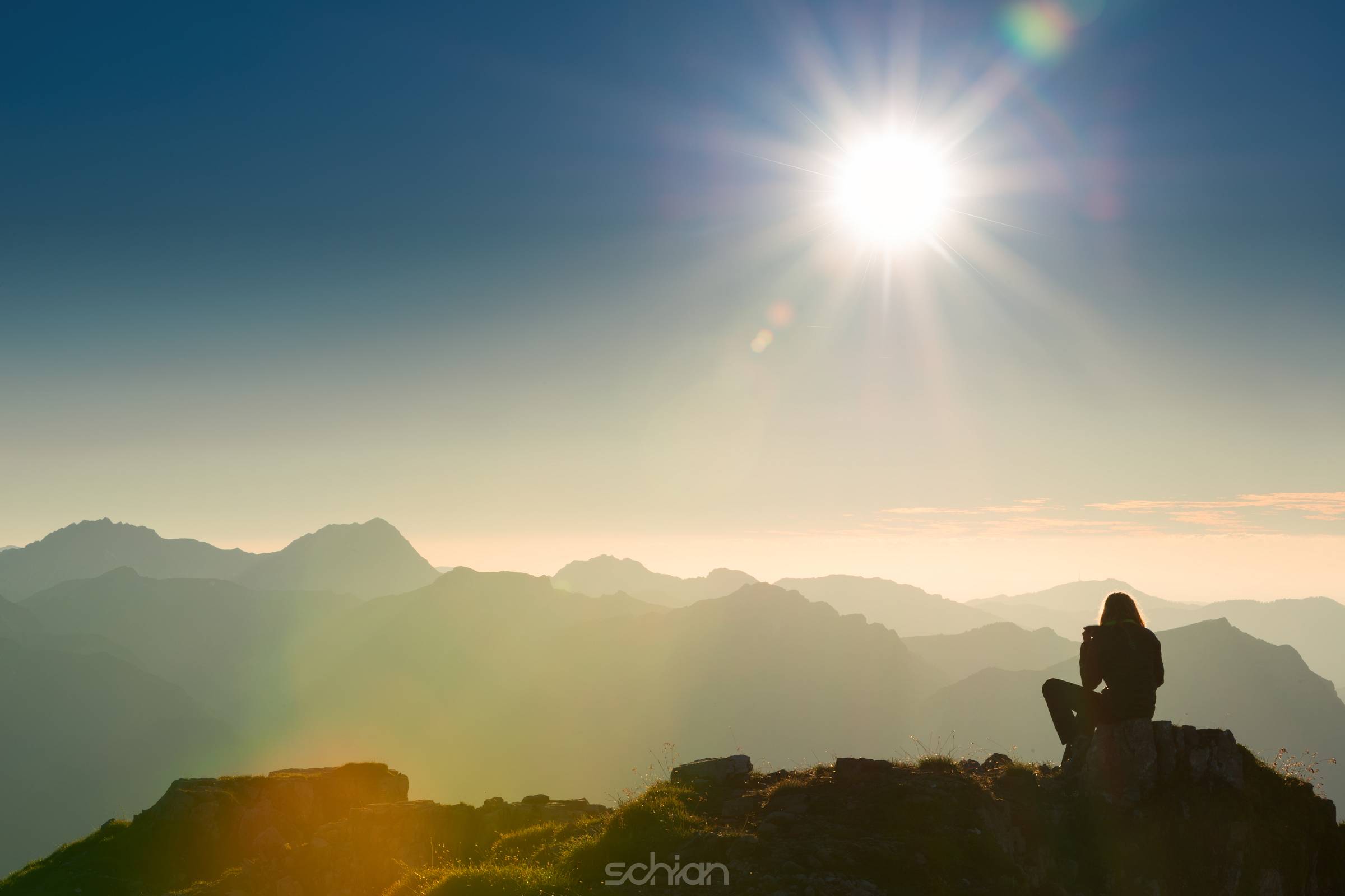 lonely sad person sits on summit of mountain at sunset 