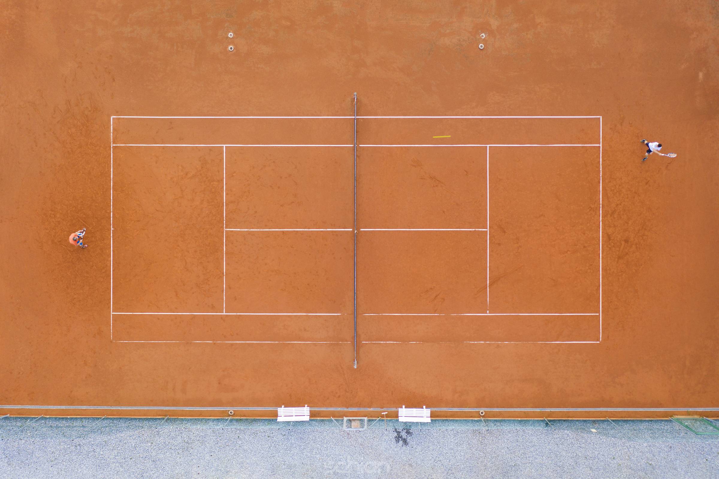 top view to orange clay court where two players play a sport tennis match