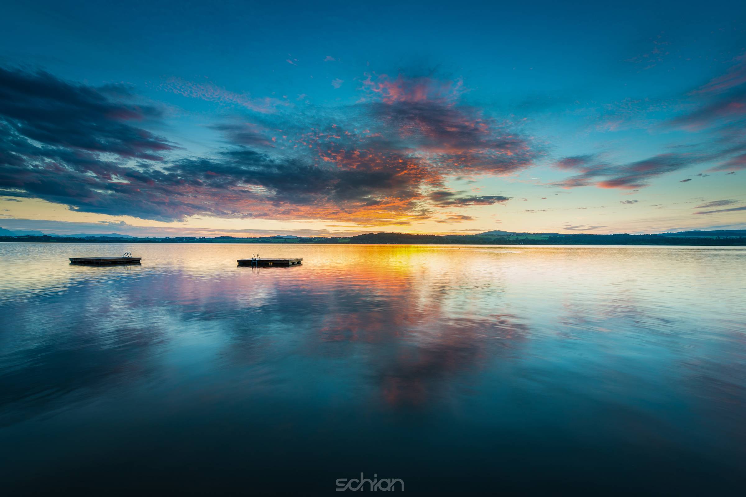 colorful clouds on sunset at lake wallersee with woodem swim platforms