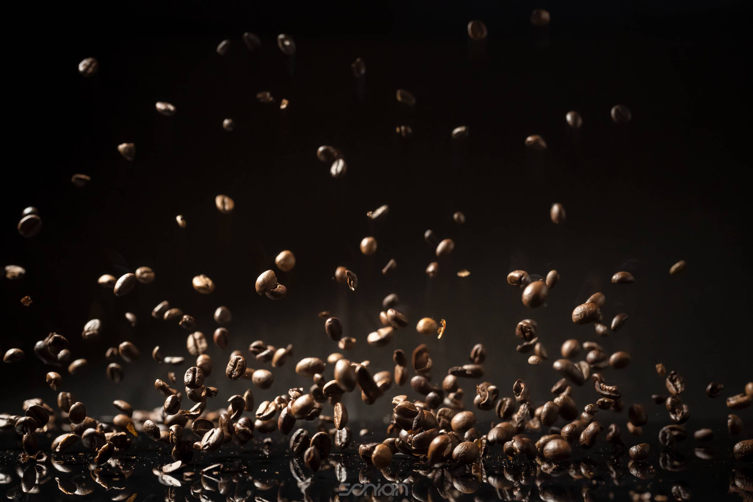 Flying weightless brown roasted coffee beans on a reflective surface and black background