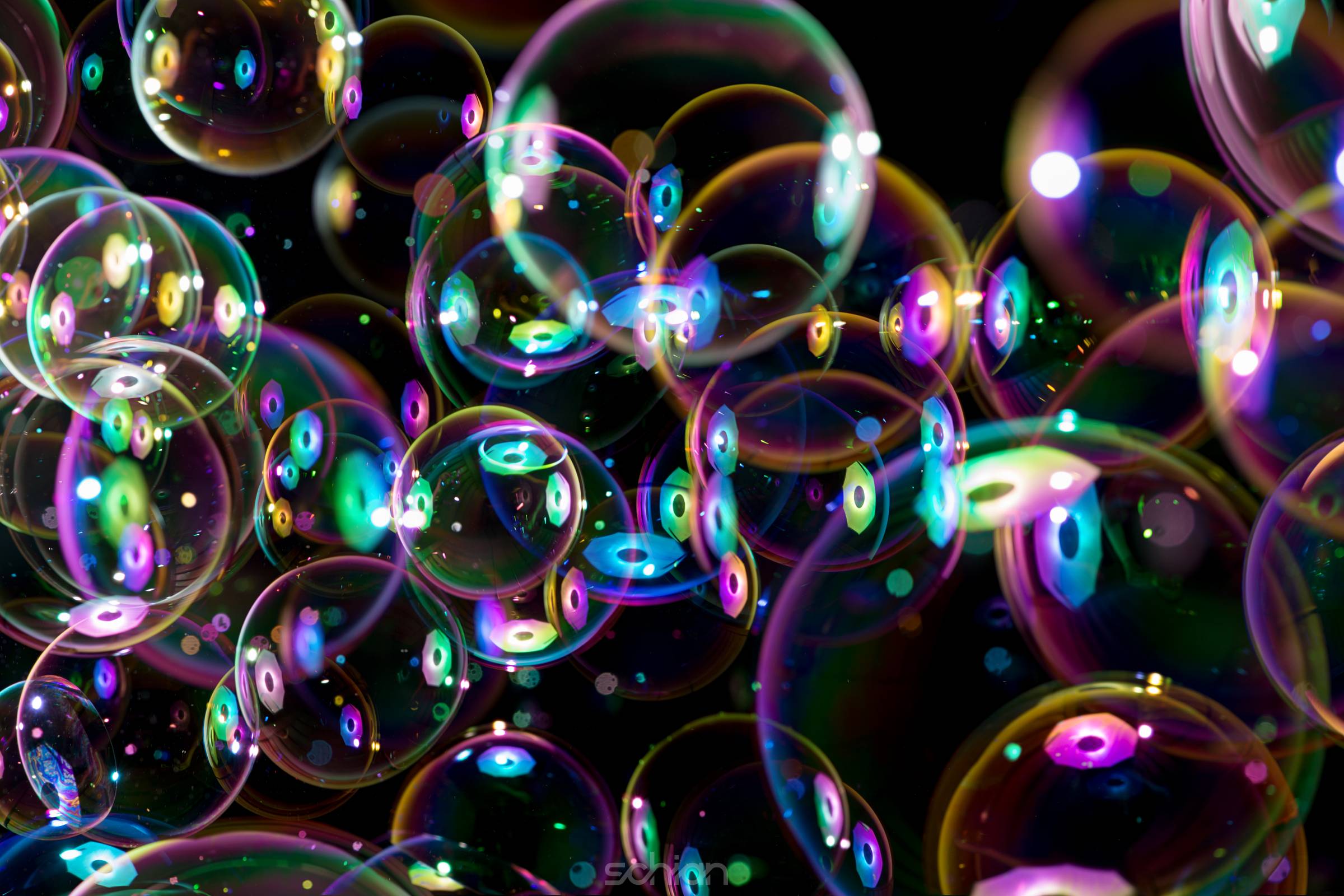 rainbow colors of flying soap bubbles on black background