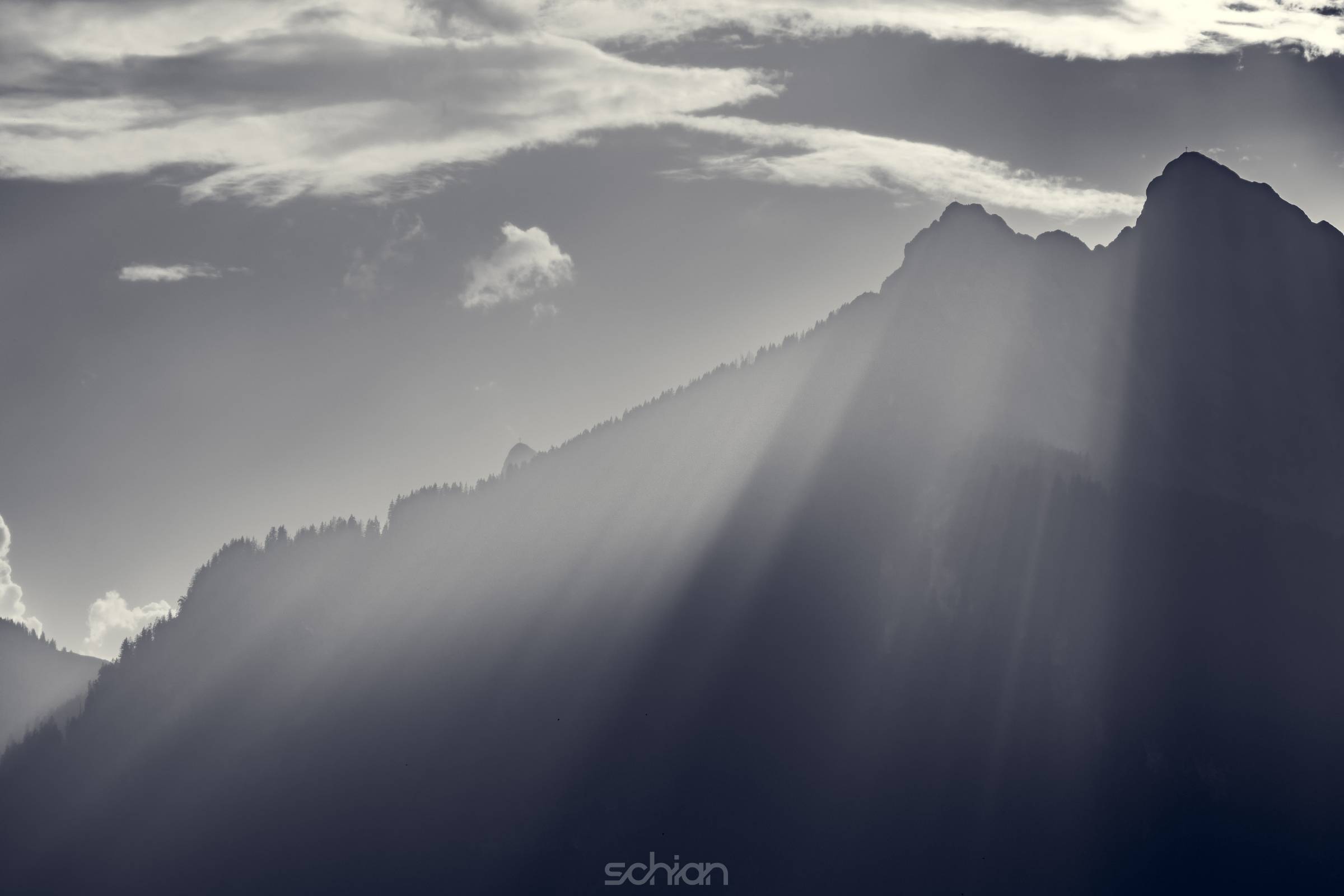 Monochrome shot of voluminous streaks of the evening sun over the ridge of the Hahnenkamm mountains in Reutte Tyrol