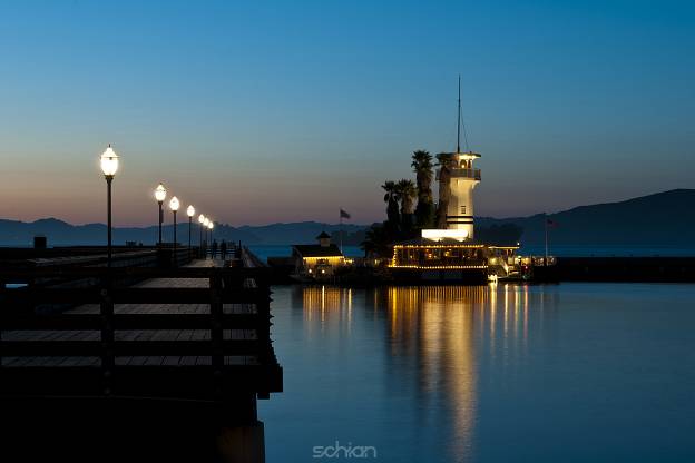 light house with integrated restaurant at the end of a footbridge by night