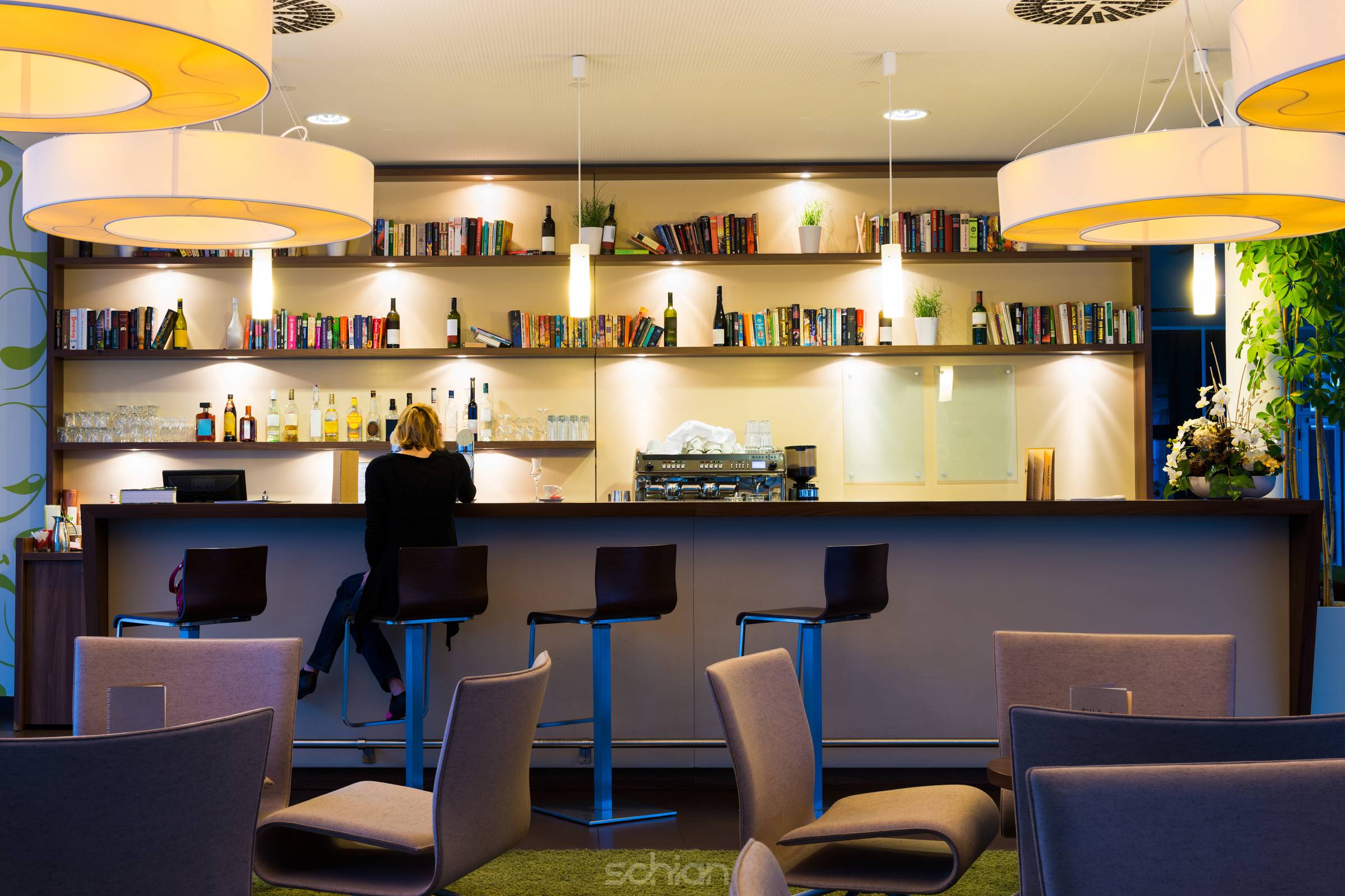 lonely girl sits alone at modern illuminated hotel bar