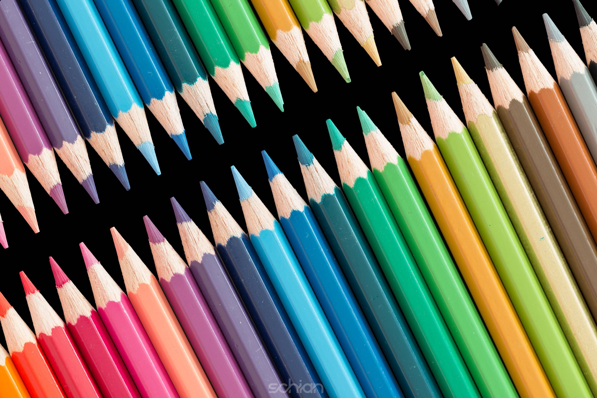 wooden color pencils lying in a row on black