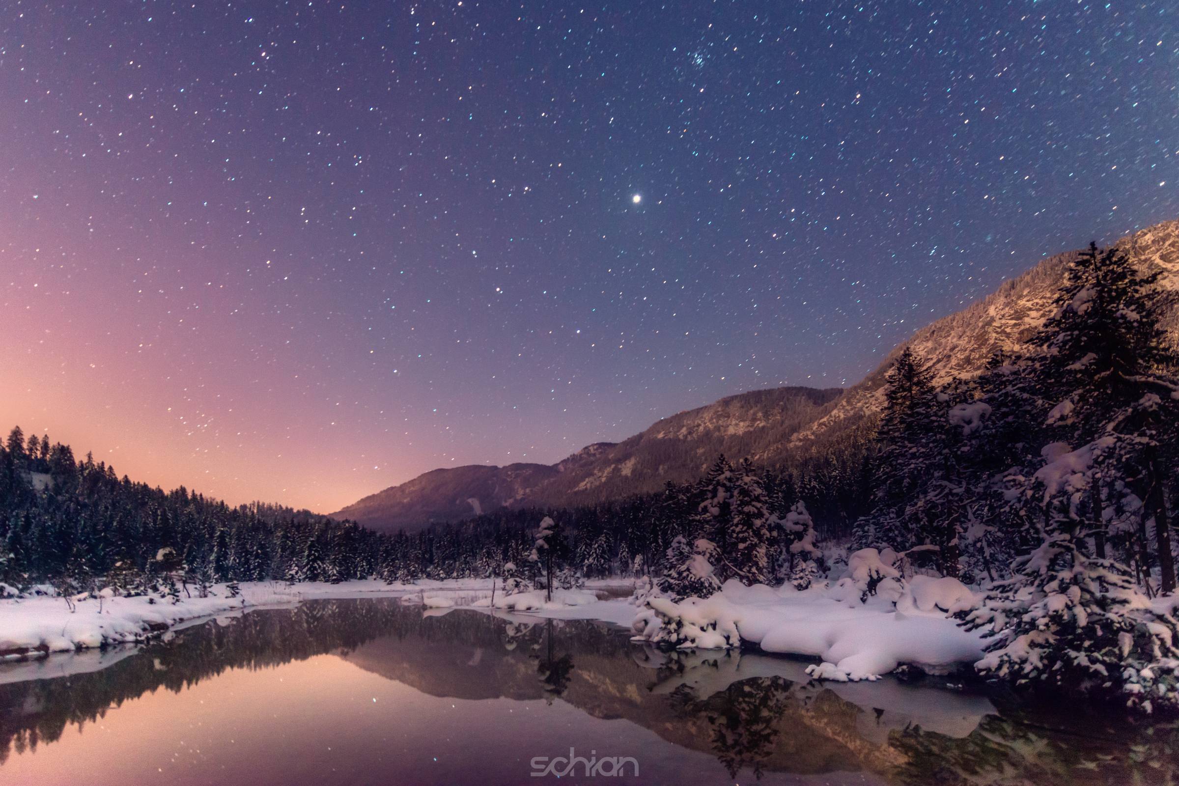 colorful winter night with stars at cold river in tirol
