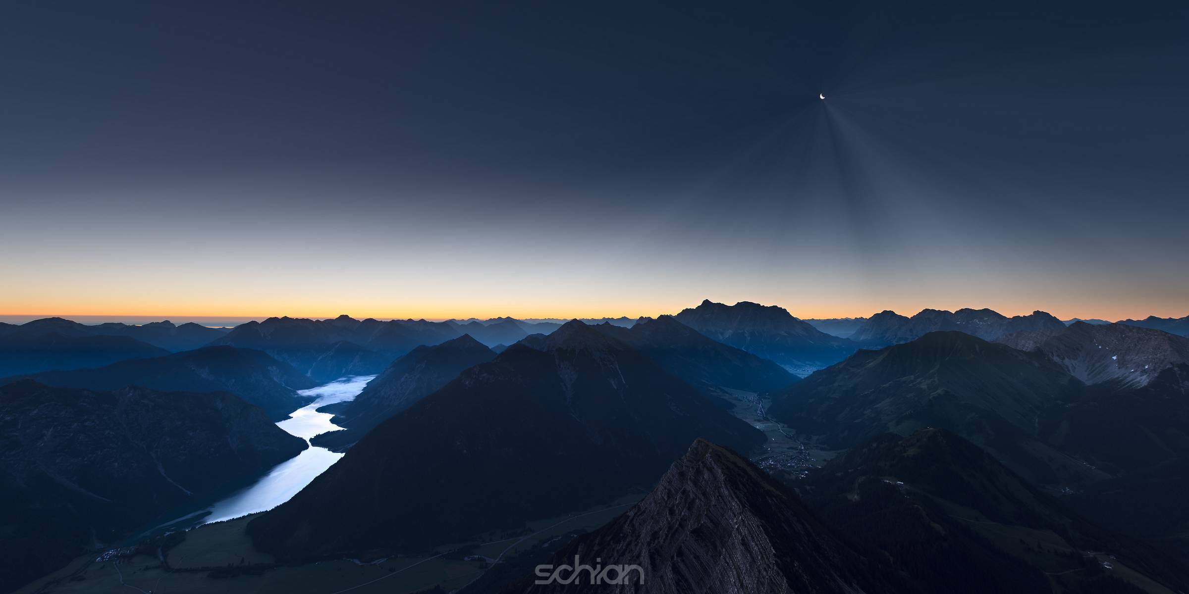 sunrise in mountains of austrian alps with moonlight and reflecting lake